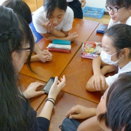 授業で使う分にはいいが…（スマートフォンを見ながら話し合う高校生と小学生）（Ｃ）共同通信社