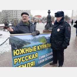 「南クリール諸島（北方領土）はロシアの土地だ」と書かれたプラカードを持つ男性（左）と警官（Ｃ）共同通信社