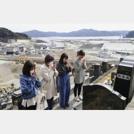 震災から８年になる前日、岩手県大槌町の高台にあるお墓を訪れ手を合わせる親子（Ｃ）共同通信社