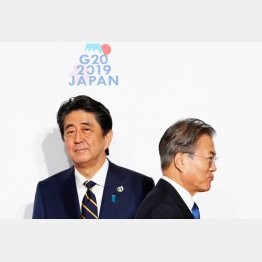 顔をこわばらせて握手（G２０大阪での安倍首相と韓国の文在寅大統領）／（Ｃ）ロイター