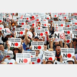 「安倍政権を糾弾する」と書かれたプラカードを手に抗議する韓国国民（Ｃ）ロイター