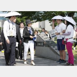 テスト大会で傘をかぶって活動するボランティア（右２人、視察に訪れた小池都知事＝左２）／（Ｃ）共同通信社