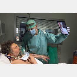 イタリア北部ブレシアの病院の集中治療室で、テレビ電話で親族と話す患者のためタブレット端末を持つ医者（Sergio Cattaneo／Brescia／Spedali Civili提供、ＡＰ＝共同）