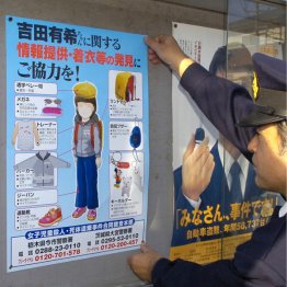 吉田有希ちゃんの情報提供を呼び掛けるポスターを張り出す警察官（Ｃ）共同通信社
