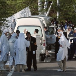 岐阜県警の捜査を受け、警察官と話す白装束の団体のメンバー(C)共同通信社